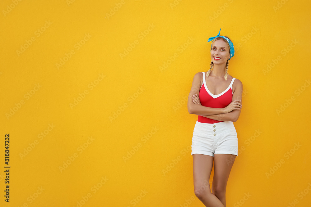 Summer urban fashion. Fun and colorful. Young pretty happy woman in shorts posing against yellow wall. - obrazy, fototapety, plakaty 