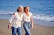 © luengo_ua - Outdoor portrait of smiling happy caucasian senior mother with her adult daughter hugging and walking on sea beach.