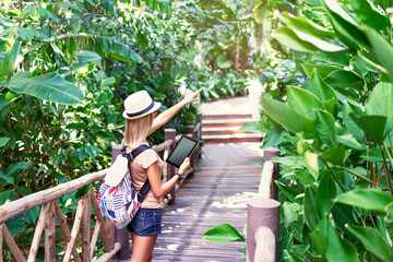 Wall Mural - Travelling concept. Technology and adventure. Young woman using tablet computer in jungle.