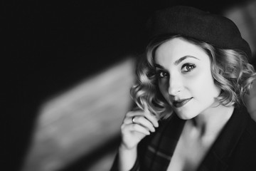 Beautiful blonde woman in a beret looks at the camera in retro style black and white photo. Close-up portrait. Soft focus.