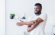 © Prostock-studio - Young black man training and stretching arm at home