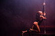 sexy young stripper with closed eyes pole dancing on black with smoke