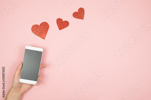 Fotomural Smart phone with blank screen in hand and hearts on old wooden table