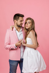 Wall Mural - happy couple in love embracing on pink background. man in a jacket and a woman in a dress are happy together. st valentines day.