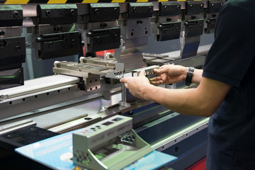 Wall Mural - Operation of press brake hydraulic bending machine with forming die by skill operator. The sheet metal manufacturing process by bending machine with technician operator.