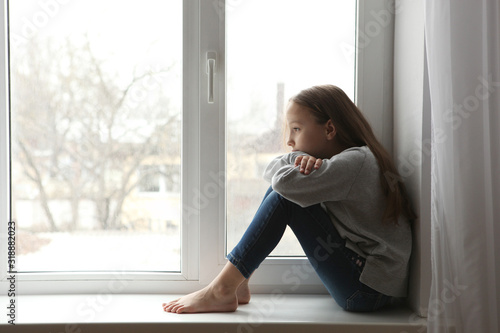 Lonely sad girl at home. The concept of loneliness. saddened alarmed child alone at home.