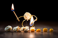 Funny Popcorn Figure Is Holding A Burning Match On Some Corns To Pop Them Up