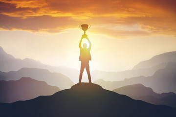 silhouette of a man holding a trophy at sunset