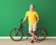 © Pixel-Shot - Stylish elderly man with bicycle near color wall