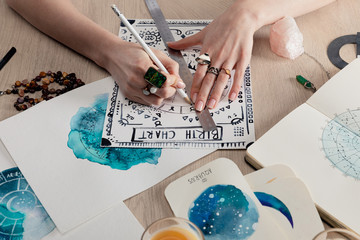 cropped view of astrologer drawing birth chart by watercolor paintings with zodiac signs on cards on