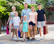 Man and woman with four kids walking and holding shopping bags