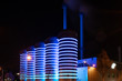 modern factory with chimneys at night. heating plant, thermal power station or power plant and silos, which are illuminated with rings of blue and purple LED lights