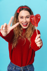 Sticker - Image of cheerful woman holding candy and gesturing peace sign