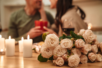 Wall Mural - Image of man giving present box to his girlfriend during romantic dinner