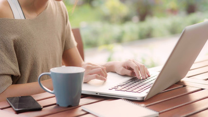 Freelance Asian woman working at home, business female working on laptop sitting on table in the garden in morning. Lifestyle women working at home concept.