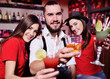 © Evgeniy Kalinovskiy - group of friends-young guy and two cute girls having fun at a party holding cocktails