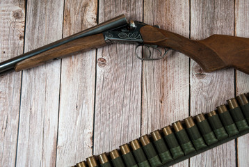 Hunting equipment. Hunting weapons and bandolier with cartridges on a light wooden background. Free space.