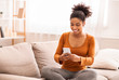 © Prostock-studio - Woman Using Phone And Earphones Sitting On Couch At Home