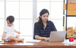 © Rakchanok - Beautiful Asian business mom is using laptop, smiling, spending time with cute baby girl at home, Single mother take care adorable child kid, working on technology computer cardboard box background