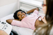 © sofiko14 - Happy smiling pregnant African American woman getting ultrasound from doctor in modern medical center