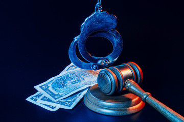 Wall Mural - Bribe concept. Dollar banknotes, handcuffs and gavel on dark black table