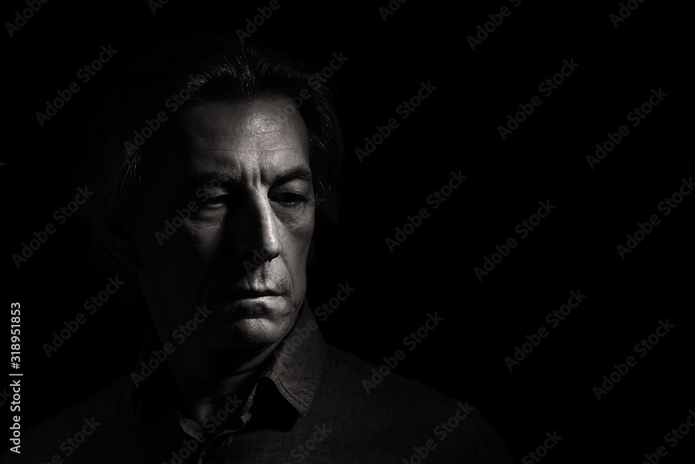 Portrait of a stern man on a black background with space for text. - obrazy, fototapety, plakaty 