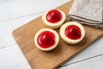 Wall Mural - Mini cheesecakes with cherry topping, healthy summer treat on grey stone table