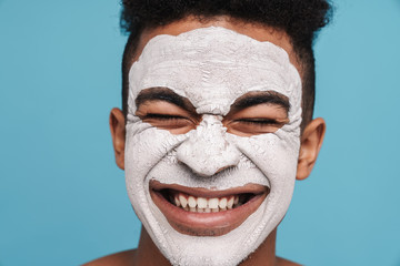 Wall Mural - Photo of excited african american man in facial mask smiling at camera