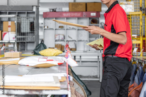 Cuadros en Lienzo Thai young postal man is sorting mail parcels at postal office.