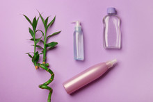 Three Cosmetic Botlles With Bamboo Branch On Purple Paper Background
