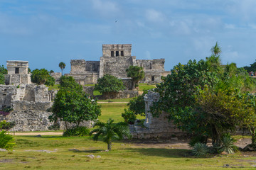 Wall Mural - Ruins of ancient Tulum. Architecture of ancient maya. View with temple and other old buildings, houses. Blue sky and lush greenery of nature. travel photo. Wallpaper or background. Yucatan. Mexico.