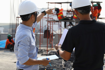 Two engineers work on the construction site. They are checking the progress of the work.