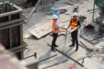 Two construction engineers shake hands in construction site