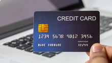Close Up Holding A Blue Credit Card Placed In Front Of The Laptop. Online Shopping Payment And Retail Concepts. Mockup And Fake Credit Card