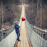 Fototapeta  - Frau mit roten Herzballon auf einer Hängebrücke
