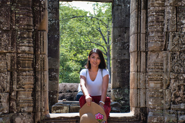 Beautiful, pretty, young Thai girl is exploring the ancient ruins of Angkor Wat (City/Capital of Temples) Hindu temple complex in Siem Reap, Cambodia. The largest religious monument in the world