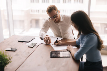 Two colleagues employees man and woman are cooperating in boardroom, talking working together at workplace, planning business project brainstorm in corporate teamwork. Concept of office life.