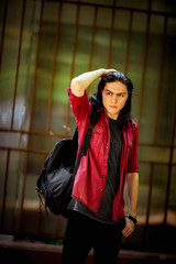 Wall Mural - a young, handsome man with long hair and brown eyes walks down the street in a bright shirt and black jeans