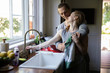 © Augustus Butera - straight caucasian millennials couple in the kitchen kissing and washing dishes in the morning making breakfast