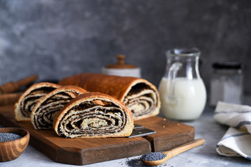 Wall Mural - Rosy roll with poppy seeds and milk on a concrete background.