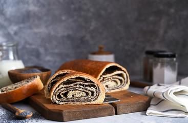 Wall Mural - Rosy roll with poppy seeds and milk on a concrete background.