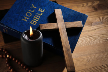 Christian cross, Bible and candle on wooden background