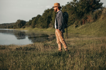 Poster - Male traveler standing by lake admiring view