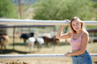 Attractive young Hispanic woman posed near horse corral - pink tank top and denim shorts