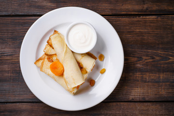 Tasty breakfast, cottage cheese filled pancakes with sour cream and raisins. Morning meals