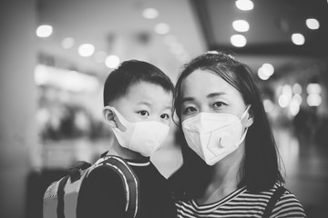 Poster - Coronavirus and Air pollution pm2.5 concept.Little chinese boy and chinese mother wearing mask for protect pm2.5 in airport terminal.Wuhan coronavirus and epidemic virus symptoms.black and white.