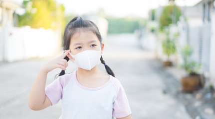 Wall Mural - Coronavirus and Air pollution pm2.5 concept.Little chinese girl wearing mask for protect pm2.5 and pointing finger at brain and thinking.Wuhan coronavirus and epidemic virus symptoms.