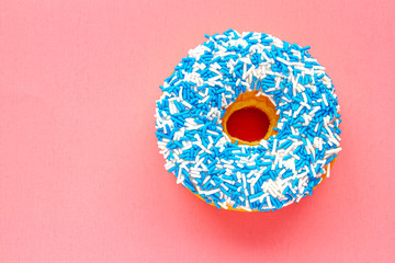 Wall Mural - A Canadian Vanilla Dip Donut with Coloured blue and white Sprinkles on a pink background.