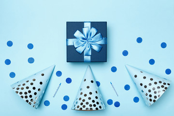 Birthday blue background composition with party gift present caps confetti candles top view flat lay