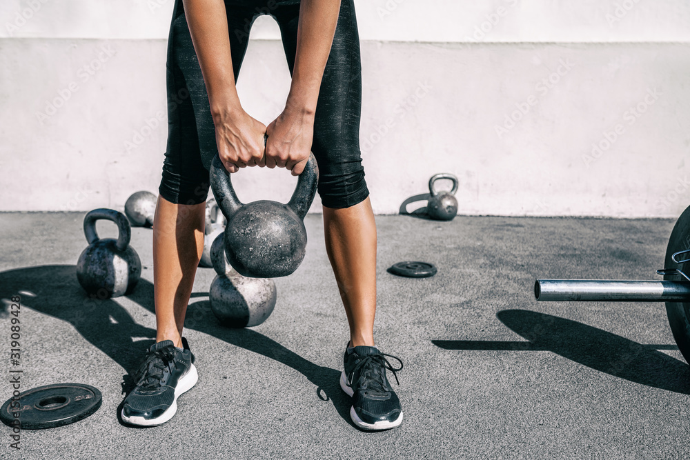 Kettlebell weightlifting athlete woman lifting weight at outdoor fitness gym. Lower body legs and feet closeup of strength training legs, glutes and back lifting free weights. - obrazy, fototapety, plakaty 